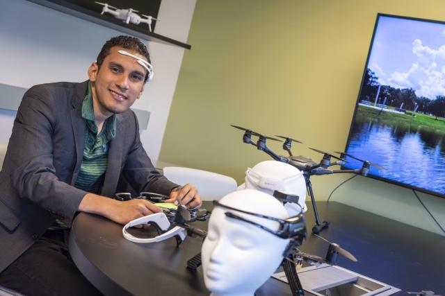 Kean alumnus Marvin Andujar demonstrates a piece of brain interface equipment