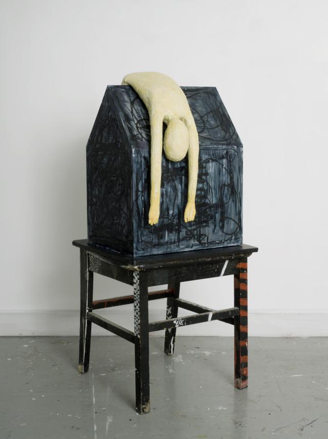 A sculpture of a pale body draped over a black house