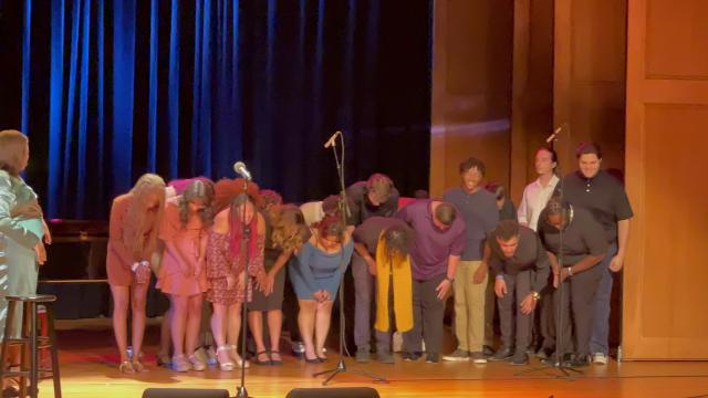 Kean students bow onstage. Alex Newell stands off to the side.