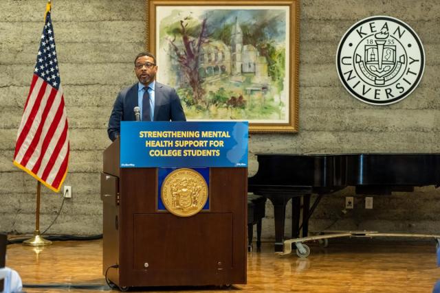 Higher Education Secretary Brian Bridges, at a podium with the sign Strengthening Mental Health Support for College Students