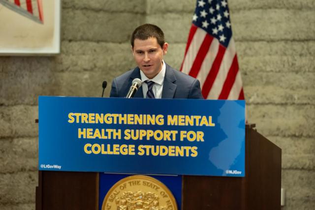 Matt Camarda, at a podium with the sign Strengthening Mental Health Support for College Students