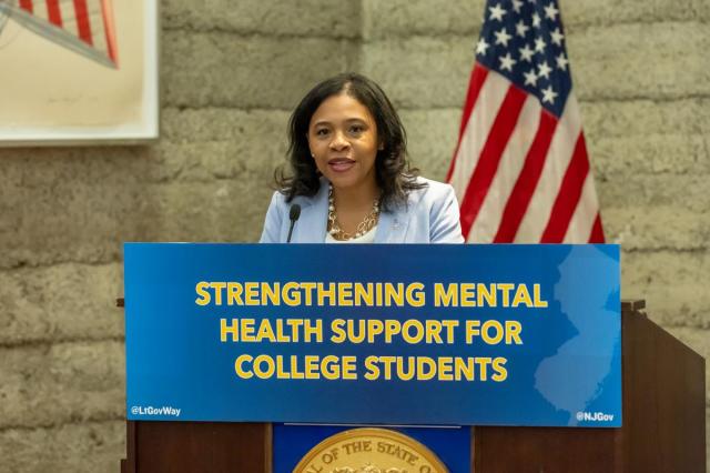 Tahesha Way speaks at a podium with the sign Strengthening Mental Health Support for College Students