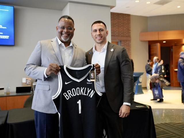 President Repollet holds up a Brooklyn Nets jersey at the Kean Sports Summit