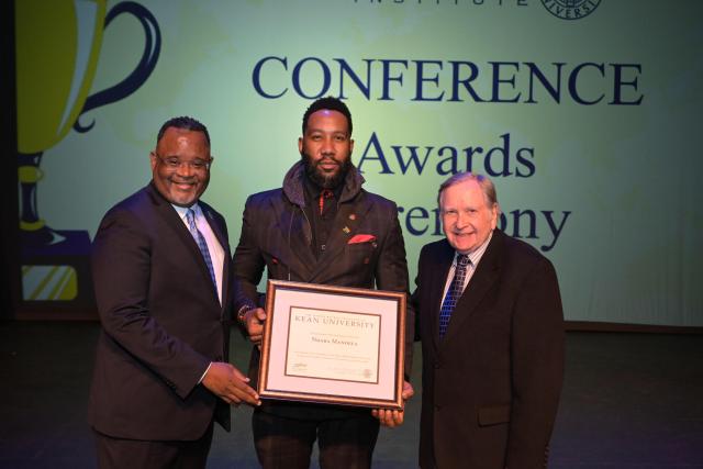 Ndaba Mandela with his award, standing next to President Repollet on his left and another gentleman on his right