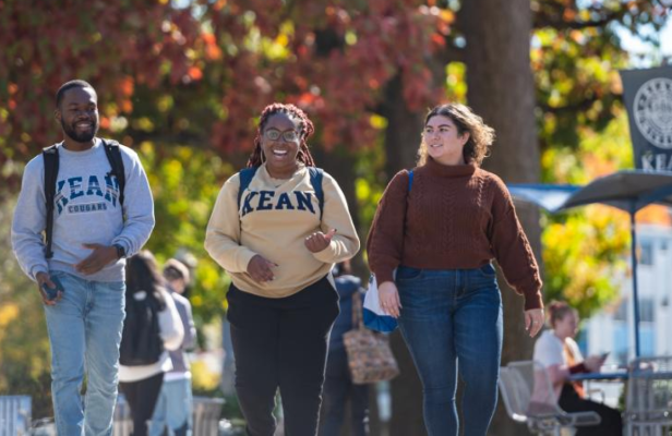 Kean students walk against a fall foliage backdrop 