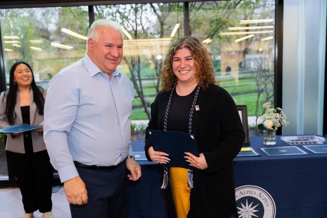 A student and her father smile after she is inducted into the honor society.