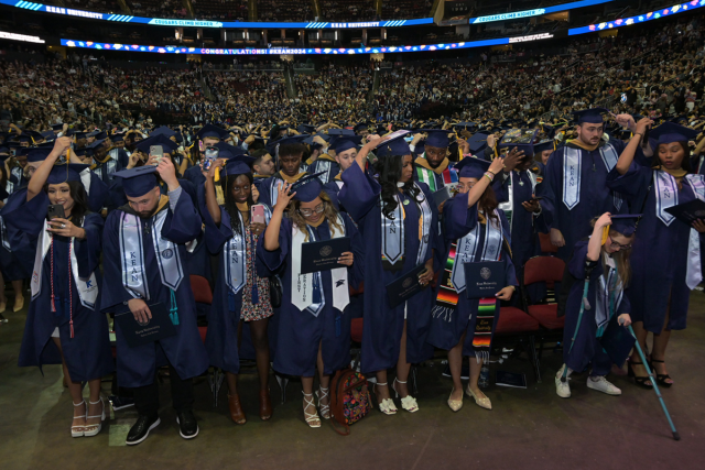 Graduates at Kean University's Undergraduate Commencement turn the tassels on their caps.