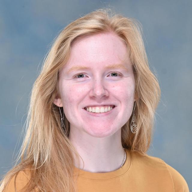 Professional headshot of Megan Olsen, Academic Specialist, wearing a mustard-yellow shirt