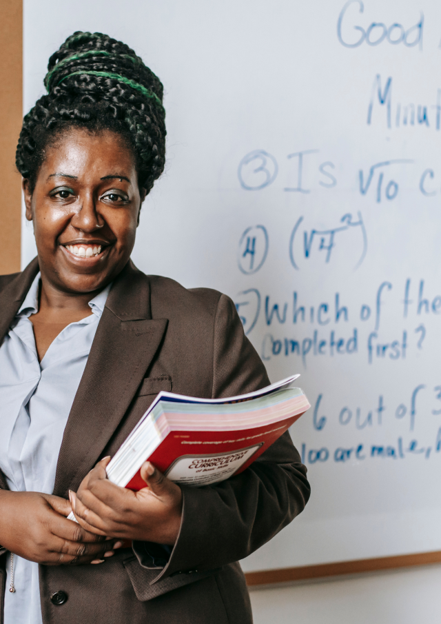 Teacher stands confident with books greeting the class 