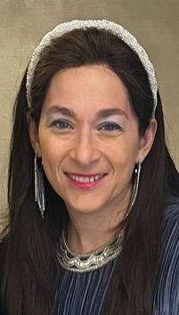 Headshot of a smiling white woman with long dark hair, wearing a blue blouse, jewelry and makeup.