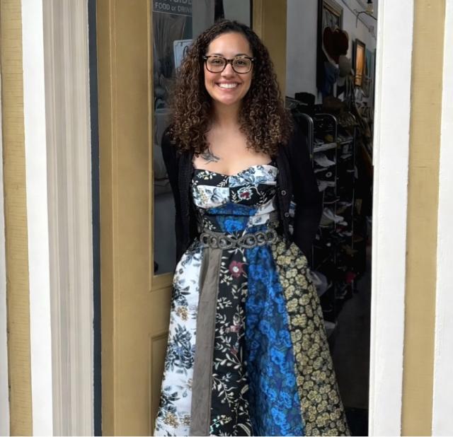 Woman with dark and glasses wearing printed dress smiling