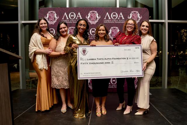 Members of Lambda Theta Alpha holding oversized check for $50,000