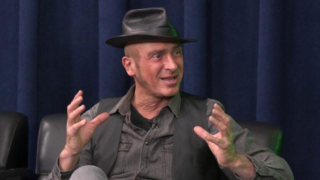 male wearing a black leather hat, black denim shirt with a black vest