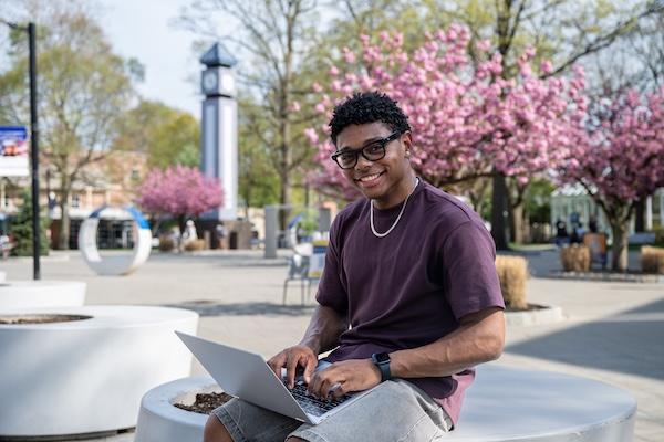 A Kean student relaxes on the MSC plaza by the clock tower. 