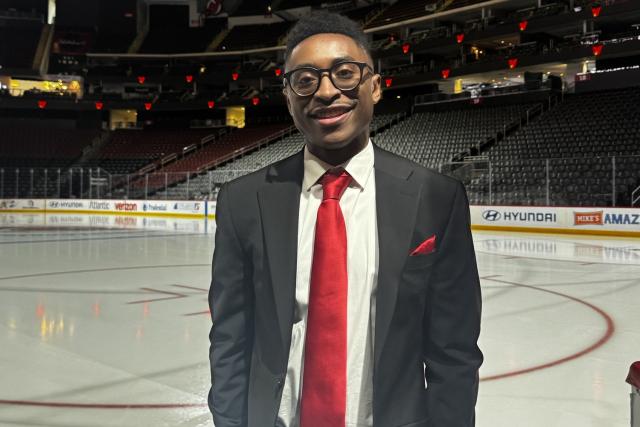 Man in a suit standing in a hockey arena