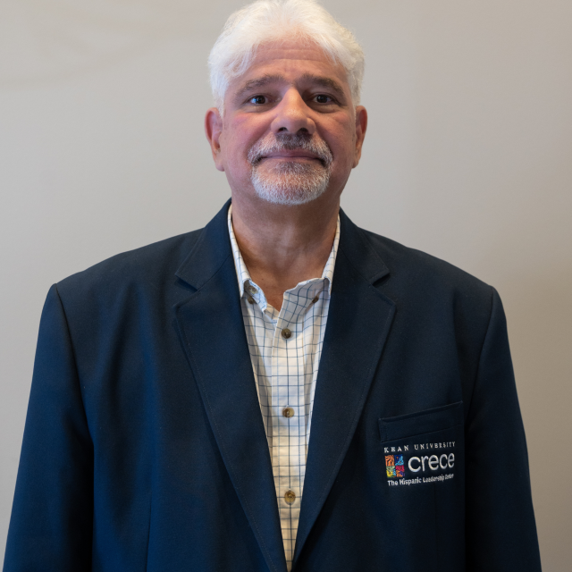 Hispanic male with white hair and short white beard in a plaid shirt and dark blue CRECE jacket