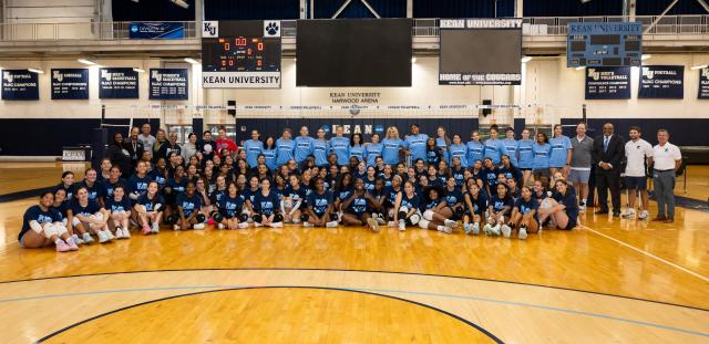 Volleyball players and coaches standing and kneeling on a court