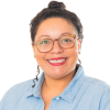 Smiling Latina woman with glasses, red lipstick and a blue shirt.