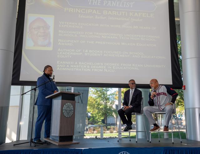 Three men speaking on stage