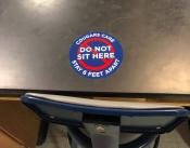 Photo of pandemic related sticker placed on lab table alerting individuals to not sit there - to stay six feet apart