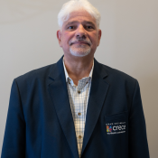 Hispanic male with white hair and short white beard in a plaid shirt and dark blue CRECE jacket
