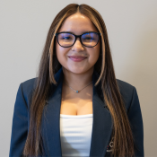 Smiling Hispanic female with long light brown hair, classes, wearing a white shirt and dark blue CRECE jacket