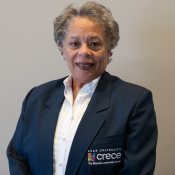 Smiling Hispanic woman with short grey hair wearing a white blouse and dark blue CRECE jacket