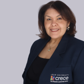 Smiling Latina woman with shoulder-length brown hair, black top and dark blue CRECE jacket