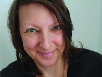  Jacquelyn Tuerk-Stonberg, Ph.D. wearing black shirt, necklace and smiling for headshot photo.